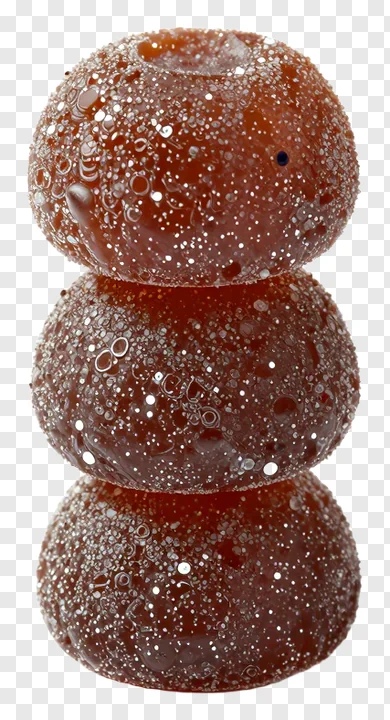 Three stacked til ladoo sweets with glittery sugar coating.
