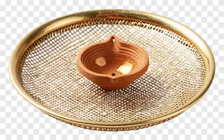 A clay diya on a golden mesh sieve.
